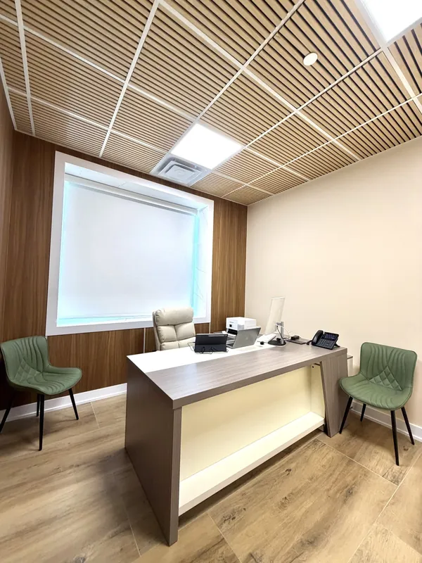 Consultation office with a wood-slat ceiling, LED panels, wood-look flooring and a custom desk