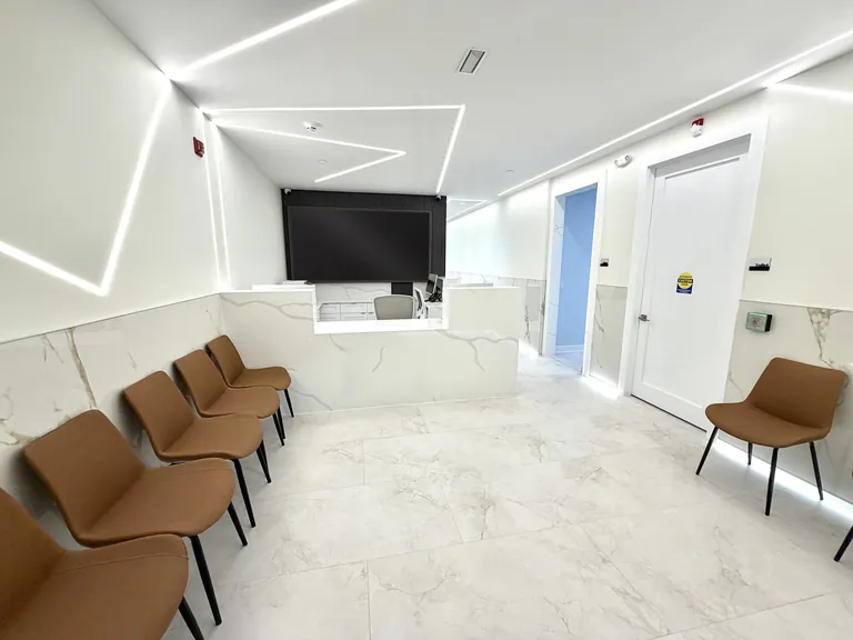 Finished commercial reception and waiting area with geometric linear LED lighting, a quartz reception desk and marble-look porcelain floors